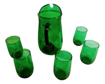 May include: A set of six green glass drinking glasses and a matching pitcher. The glasses are all the same size and shape, and the pitcher has a handle.