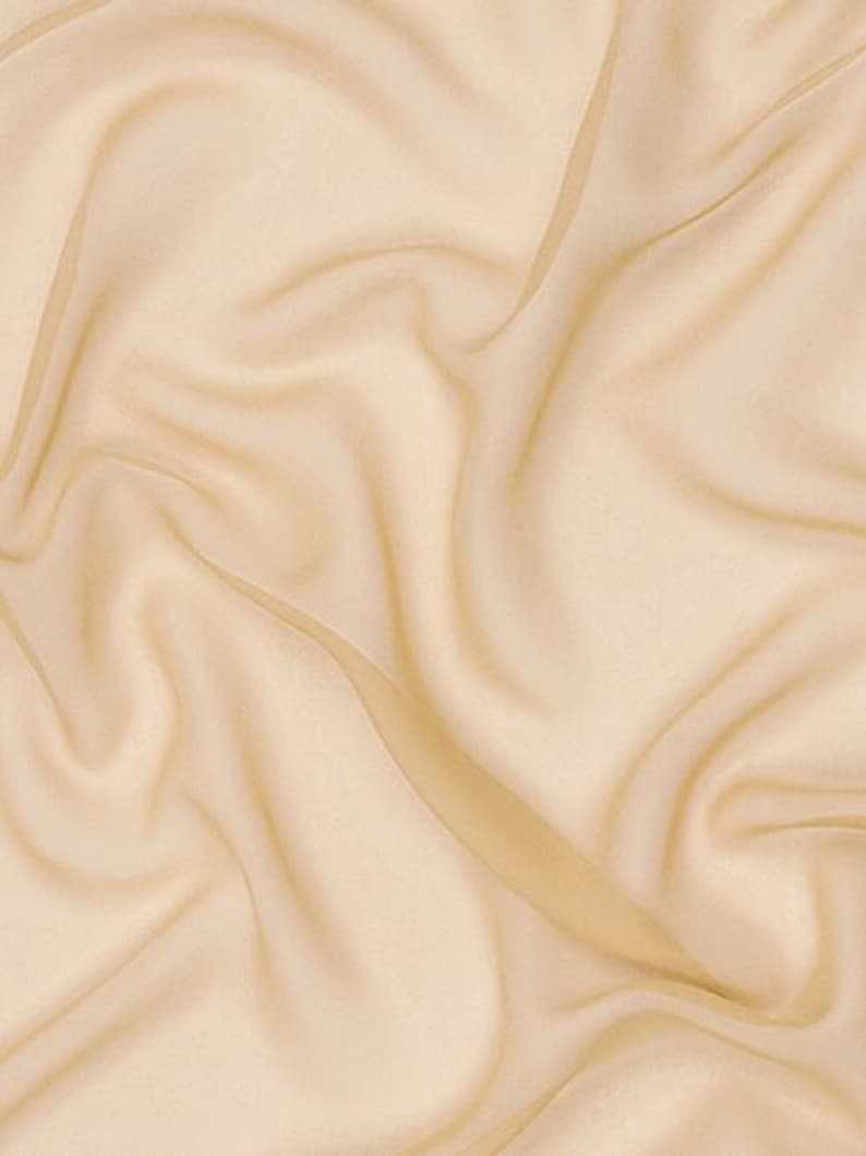 May include: A solid light beige fabric with a smooth, semi-sheer texture. The material is draped in soft, flowing folds that create subtle shadows and highlights across the surface, emphasising the delicate and lightweight nature of the textile.