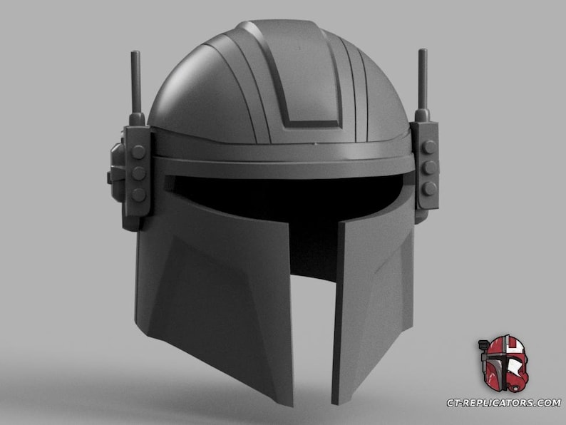 Puede incluir: Un casco gris de Mandaloriano con visor en T y protuberancias tipo antena. El casco tiene una parte superior redondeada con crestas verticales y detalles laterales. El dise&ntilde;o recuerda a la serie Star Wars.