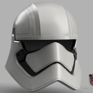 May include: A silver First Order Stormtrooper helmet with a black visor and mouth grill. The helmet has a smooth, metallic finish with detailed lines on the top. The image is set against a grey background. A small logo is in the bottom right corner.