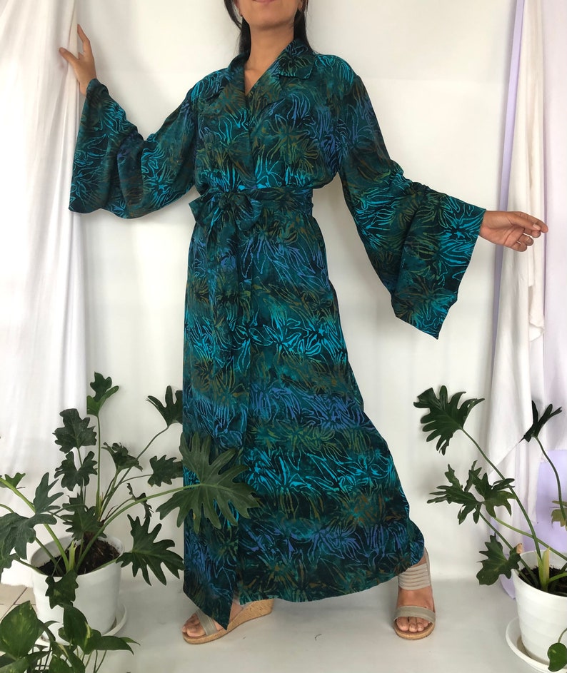 May include: A long, teal blue and green floral print robe with a tie belt and wide bell sleeves.