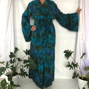May include: A long, teal blue robe with a floral print and a tie belt. The robe has long sleeves with wide cuffs.