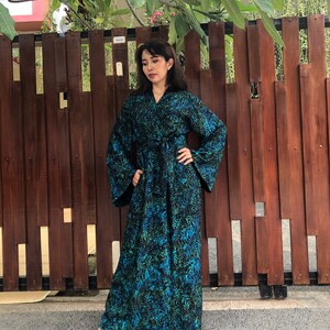 May include: A long, flowing robe with a blue and green floral print. The robe has a tie belt and long sleeves.