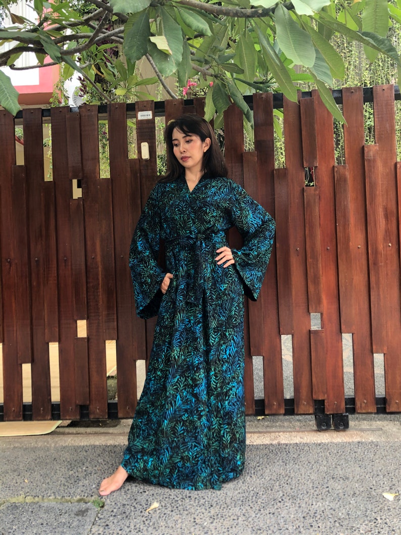 May include: A long, flowing robe with a blue and green floral print. The robe has a tie belt and long sleeves.