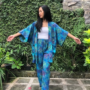 May include: A blue and green patterned kimono with a white top and matching pants. The kimono has a wide, flowing sleeve and a relaxed fit.