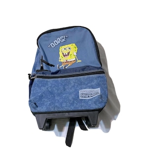 May include: Blue rolling backpack featuring a SpongeBob SquarePants design. The backpack has a cartoon image of SpongeBob and the word "OOPS!" printed on the top flap. The bottom section has the words "SpongeBob SquarePants".