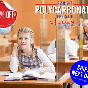 May include: A clear plastic desk shield with the text "RESILIENT POLYCARBONATE FIRE RATED" and "STUDENT GUARD" in red, white, and blue. The shield is in a classroom setting with two students sitting at desks.