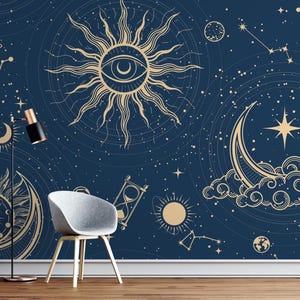 May include: Dark blue celestial-themed wallpaper featuring gold suns, moons, stars, and constellations. A gray chair and a black and gold floor lamp are in front of the wallpaper. The wallpaper has a mystical, cosmic design.
