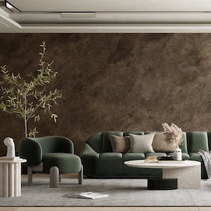 May include: A living room interior design with a green velvet sofa and armchair, a coffee table with a textured surface, and a potted plant. The room has a brown textured wall and a rug on the floor.