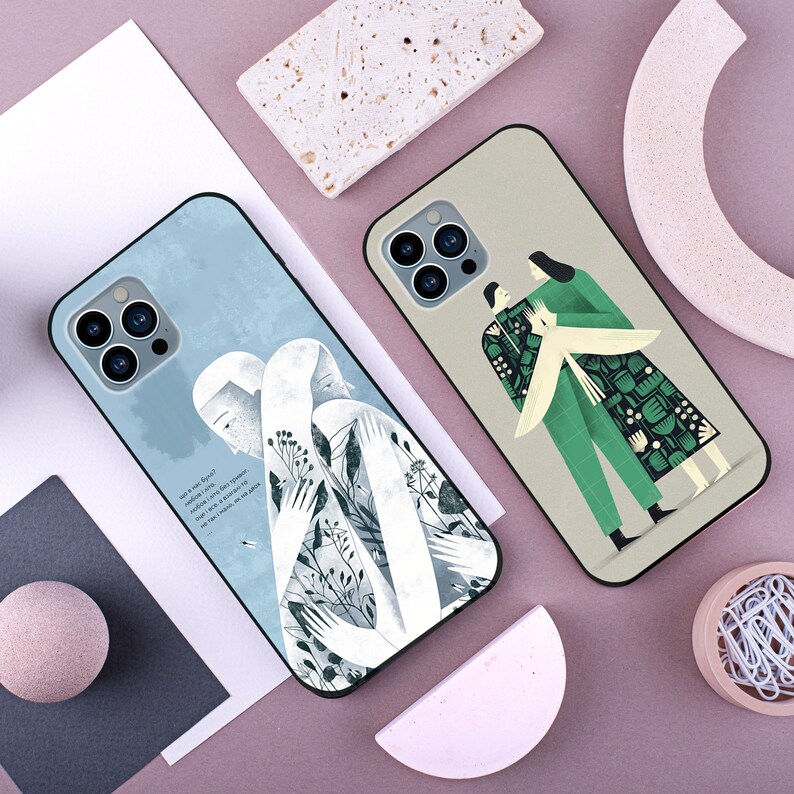 May include: Two phone cases with different designs. One case features a white silhouette of two people embracing with a blue and white background. The other case features two people in green and black clothing with a floral pattern on a beige background. Both cases have a black border and a camera cutout.