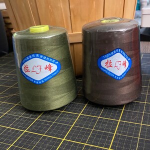 May include: Two spools of thread, one green and one brown, with the text "拉LF峰" and "100%纯涤纶高速缝包机线" on the labels.