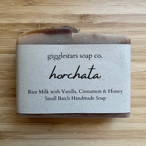 May include: A brown bar of soap with a white label that reads "gigglestars soap co. horchata Rice Milk with Vanilla, Cinnamon & Honey Small Batch Handmade Soap".