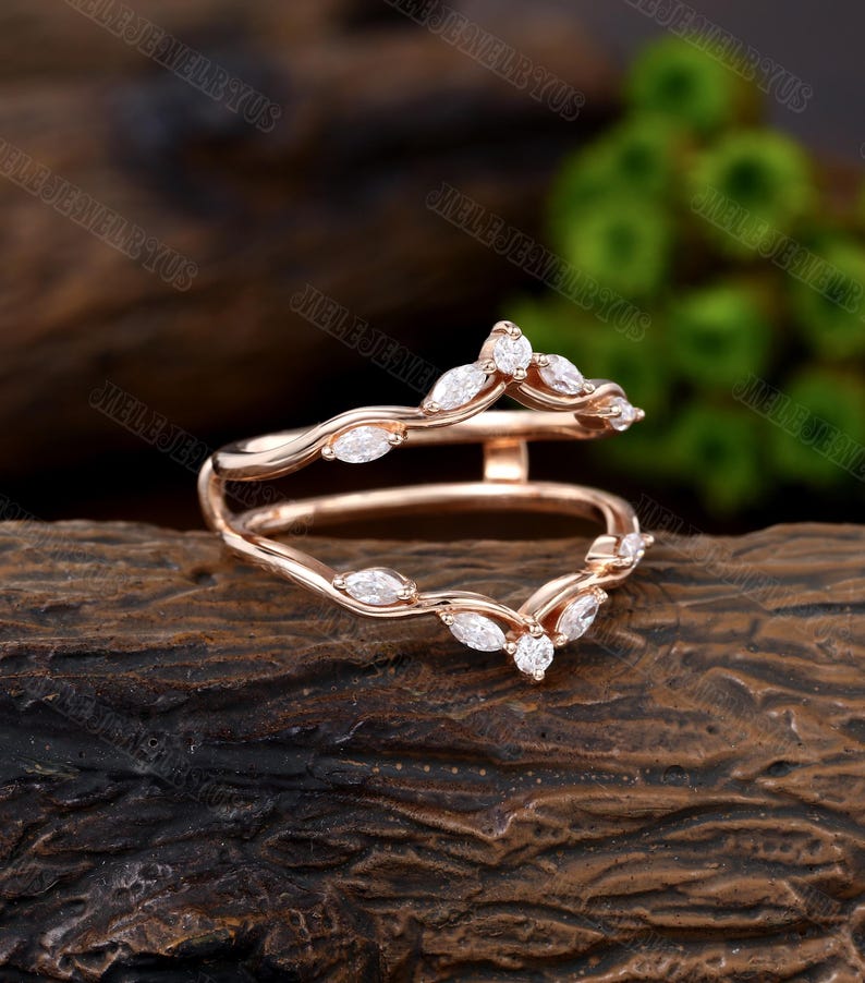 May include: A rose gold ring with a delicate, curved design. The ring is set with marquise-shaped diamonds, which are arranged in a pattern that resembles a vine. The ring is a beautiful and elegant piece of jewelry.