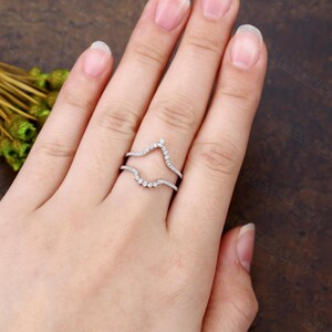 May include: A delicate, curved diamond ring setting, designed to hold a center stone. The setting is made of white gold and features a row of small diamonds on each side.