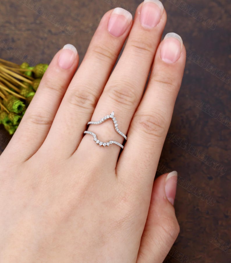 May include: A delicate, curved diamond ring setting, designed to hold a center stone. The setting is made of white gold and features a row of small diamonds on each side.