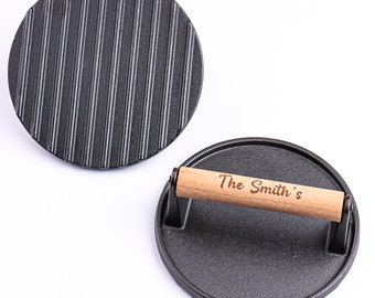 May include: Two black cast iron burger press, one with a wooden handle engraved with "The Smith's".