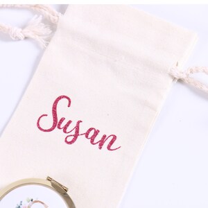 May include: A white cotton drawstring bag with the name "Susan" embroidered in pink glitter on the front.