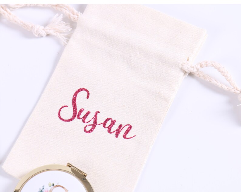 May include: A white cotton drawstring bag with the name "Susan" embroidered in pink glitter on the front.