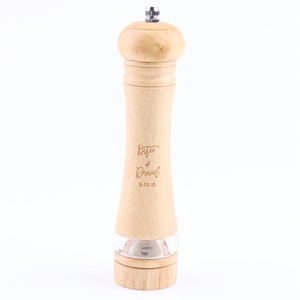 May include: A wooden pepper mill with a clear glass bottom and a silver top. The mill is engraved with the text "Katie & Daniel 9-25-22".
