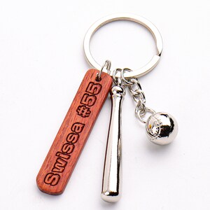 May include: A silver baseball bat and ball keychain with a wooden tag that says "Swissa #55".