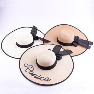 May include: Three wide-brimmed straw hats with black ribbon and bows. One hat has the name "Renica" embroidered on the brim.