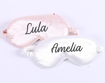 May include: Two satin sleep masks, one pink and one white, with the names "Lula" and "Amelia" embroidered on them.