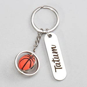 Può includere: Portachiavi in ​​argento con un ciondolo a forma di pallacanestro rotante e un'etichetta in argento incisa con il nome Tatum.