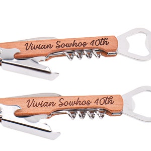 Może przedstawiać: Dwa otwieracze do butelek z drewnianym uchwytem, korkociągiem i otwieraczem do butelek. Uchwyt jest grawerowany tekstem "Vivian Sowhos 40th".