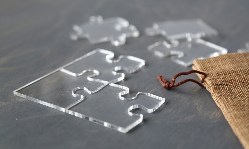 May include: A set of clear acrylic puzzle pieces with a brown drawstring bag. The puzzle pieces are shaped like jigsaw pieces.
