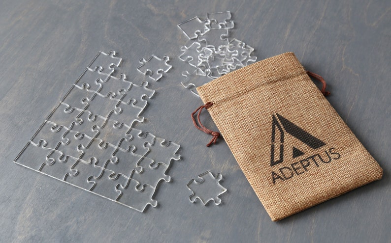 May include: A clear acrylic jigsaw puzzle with a burlap bag featuring the logo "ADEPPTUS" printed in black.