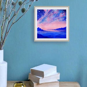 May include: A framed painting of a pink and blue landscape with a starry sky and a body of water in the foreground.