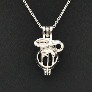 May include: A silver chain necklace with a silver charm pendant. The charm is a round cage with a small butterfly design on top.