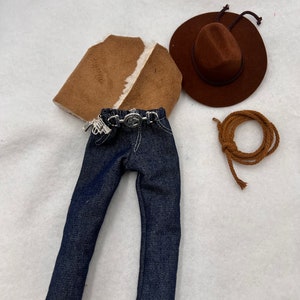 May include: A brown suede jacket with a faux fur lining, blue denim jeans, a brown cowboy hat, and a brown rope.