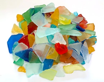 May include: A collection of colorful sea glass pieces in various shapes and sizes. The glass is translucent and has a variety of colors, including blue, green, yellow, red, and orange.