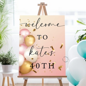 May include: Welcome to Kate's 40th birthday party sign with a pink and gold ombre background and gold confetti. The sign features a cluster of pink, gold, and white balloons.