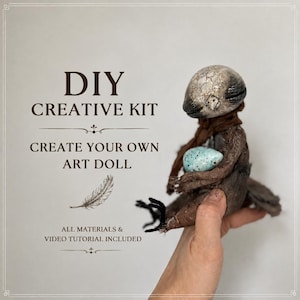 Könnte beinhalten: Ein DIY-Kreativset für eine Kunstpuppe mit dem Text DIY CREATIVE KIT CREATE YOUR OWN ART DOLL ALL MATERIALS & VIDEO TUTORIAL INCLUDED. Das Set enthält eine kleine, texturierte, grauköpfige Puppe, die ein gesprenkeltes blaues Ei hält.