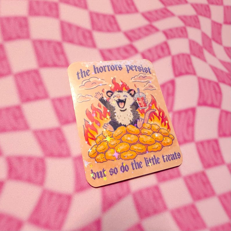 funny possum meme sticker sitting in flames on nuggets with text the horrors persist but so do the little treats pink aesthetic background.
