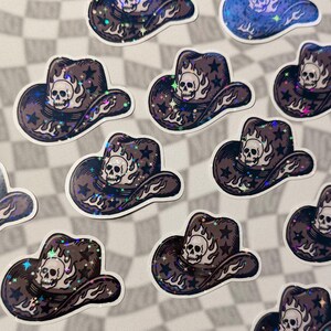 Scattered skull cowboy hat stickers with emo western aesthetic on a grey checkered surface.