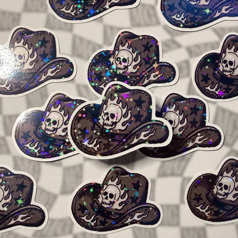 Multiple holographic sticker shaped like a cowboy hat with a skull in the center on a grey checkered background.