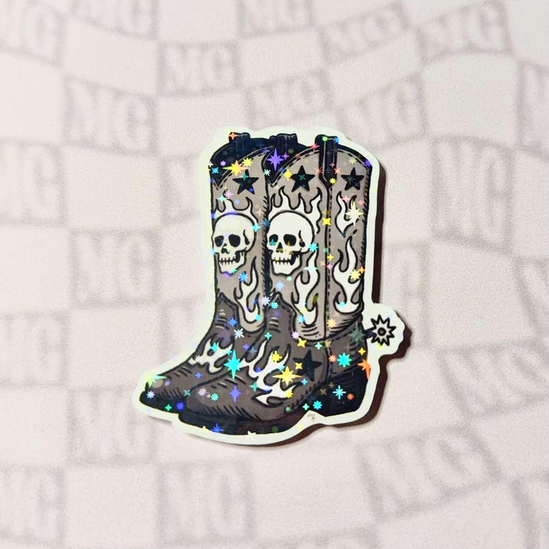 A single grayscale cowboy boots sticker displayed on a flat gray background. The boots feature skull, star, and flame motifs that blend Western and punk influences.