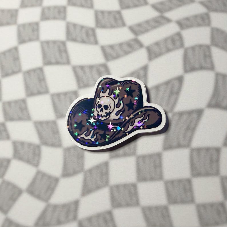 Single skull cowboy hat sticker featuring western flame and star details on a grey checkered backdrop.