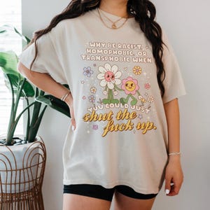 Model wearing Sand tee of why be racist, homophobic, or transphobic when you could just shut the f up tee.