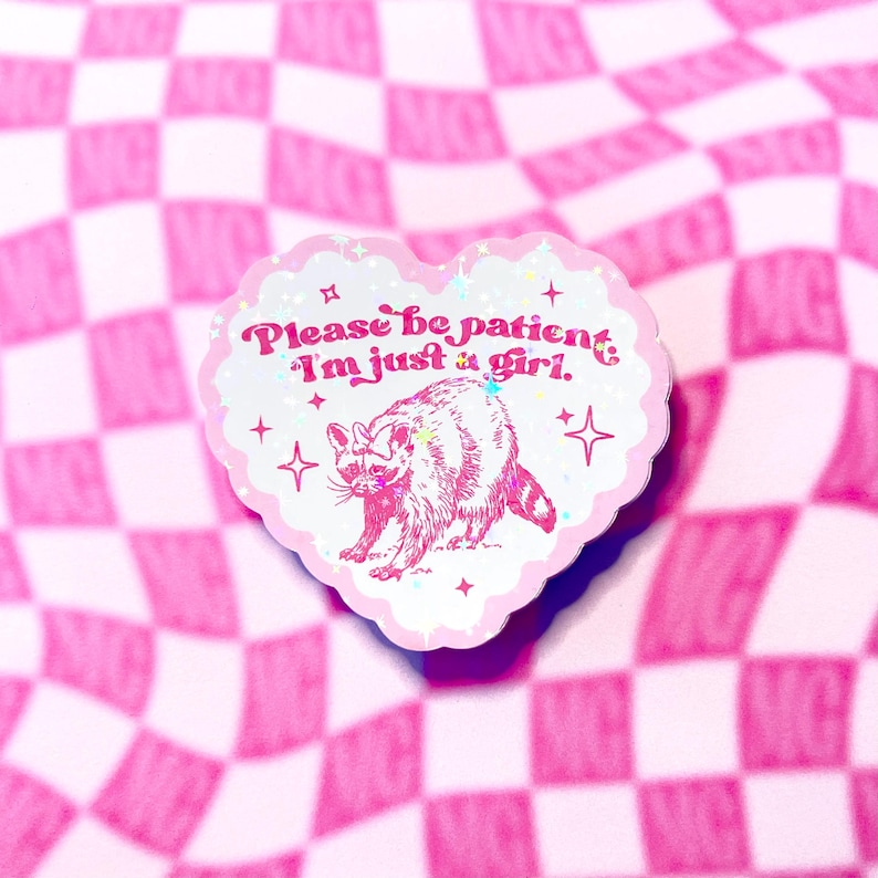 Peut inclure: Autocollant en forme de c&oelig;ur rose avec une finition paillet&eacute;e. L'autocollant repr&eacute;sente un raton laveur de dessin anim&eacute; et le texte "S'il vous pla&icirc;t, soyez patient, je suis juste une fille."