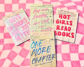 May include: Three vintage-style library cards with text. One card reads "BOYS IN BOOKS ARE JUST BETTER" in pink. Another says "buy me books and tell me pretty lies" in pink. The third card says "HOT GIRLS READ BOOKS" in red.