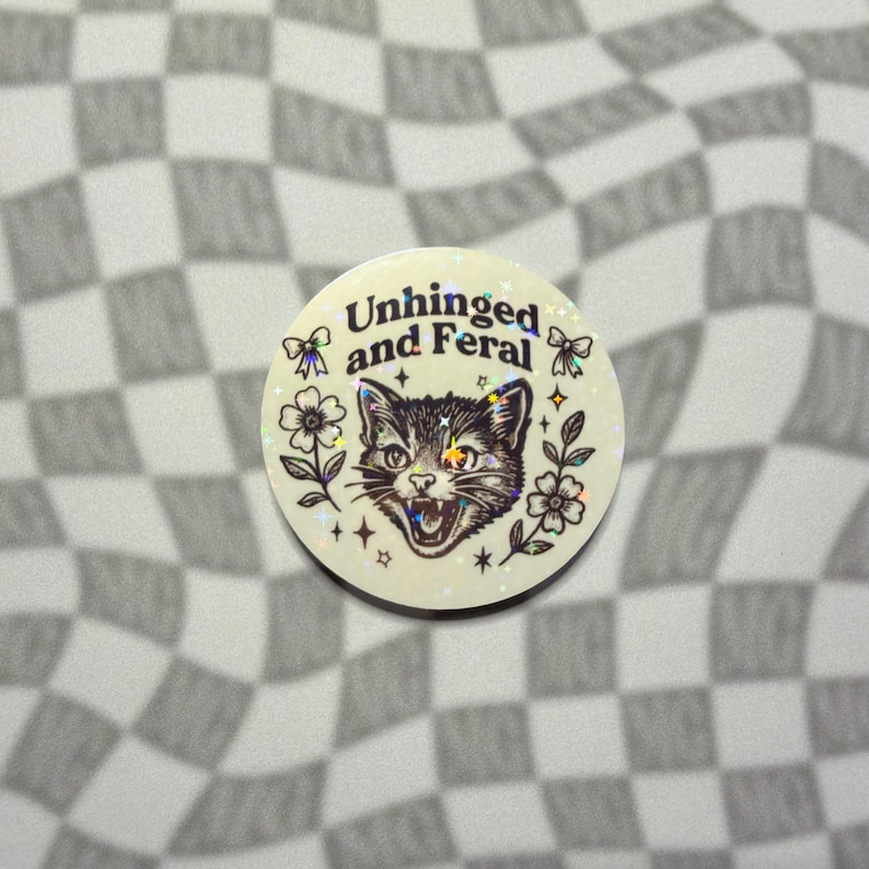 Holographic unhinged and feral cat sticker with angry kitty face flowers and bows.