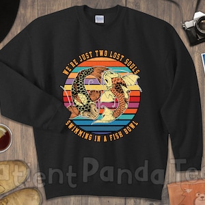 May include: Black sweatshirt with a vintage-style graphic of two fish swimming in a fishbowl. The graphic has a rainbow color scheme and the text "We're just two lost souls swimming in a fish bowl".