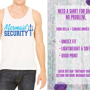 May include: White tank top with blue text that reads "Mermaid Security" and a blue trident graphic.  The tank top is on a model wearing blue jeans.