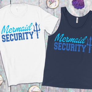 May include: A white t-shirt and a navy blue tank top with the text "Mermaid Security" in blue and a blue trident graphic.