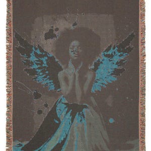 May include: A woven throw blanket featuring an artistic depiction of a figure with teal-colored wings. The figure is set against a dark background with teal accents. The blanket has a fringed edge in shades of brown and tan.