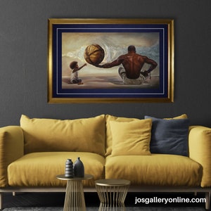 Pode incluir: Uma obra de arte emoldurada retrata uma figura sentada oferecendo uma bola a uma crian&ccedil;a. A pintura tem uma moldura dourada com um passe-partout azul marinho. A obra de arte &eacute; exibida acima de um sof&aacute; amarelo com almofadas decorativas e pequenas mesas laterais douradas. O site "josgalleryonline.com" &eacute; vis&iacute;vel.